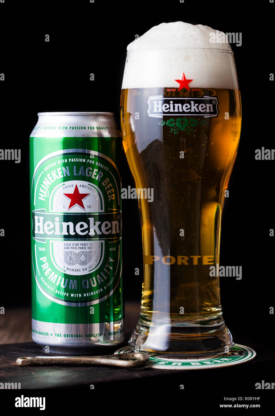 LONDON, UK - APRIL 27, 2018: Aluminium can and original glass of Heineken Lager Beer on dark wooden background. Heineken is the flagship product of He Stock Photo