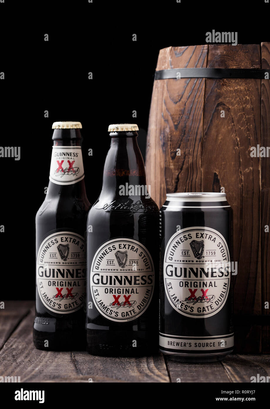LONDON, UK - APRIL 27, 2018: Aluminium can and bottles of Guinness extra stout beer  next to old wooden barrel. Guinness beer has been produced since  Stock Photo