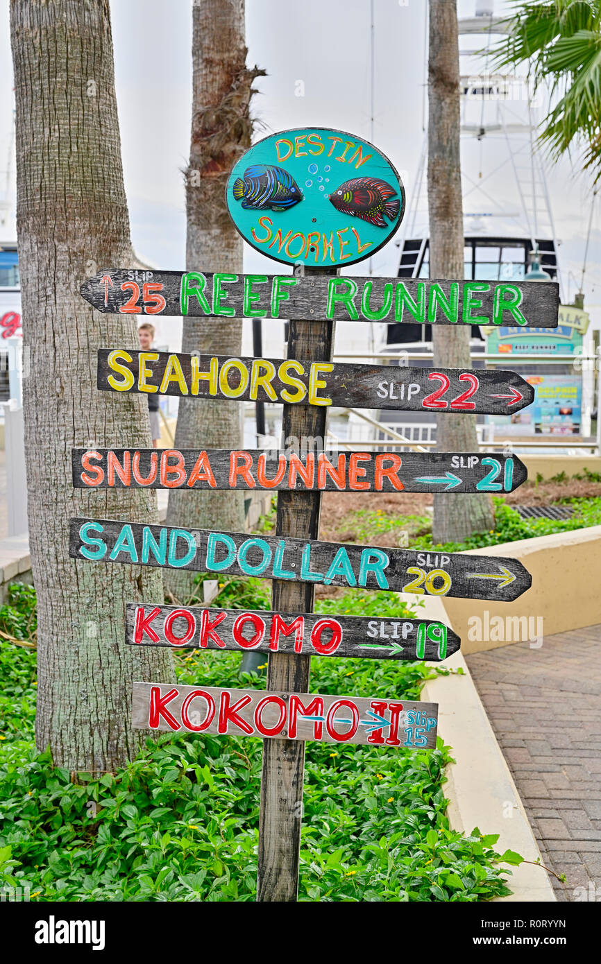 Colorful directional sign or signs pointing to charter fishing boat slips for the commercial fishing fleet at HarborWalk Marina in Destin Florida USA. Stock Photo