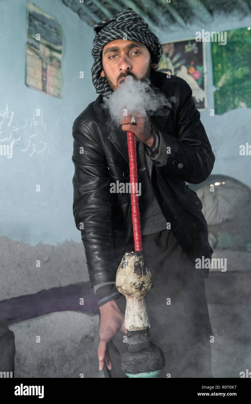 Man smoking hashish with a bong near the tomb of a Sufi saint, Ancient Balkh, North Afghanistan Stock Photo