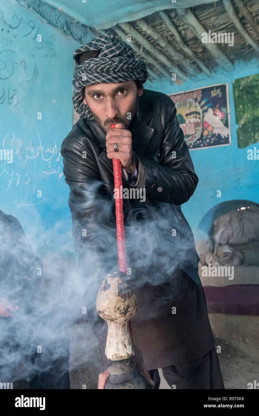 Man smoking hashish with a bong near the tomb of a Sufi saint, Ancient Balkh, North Afghanistan Stock Photo