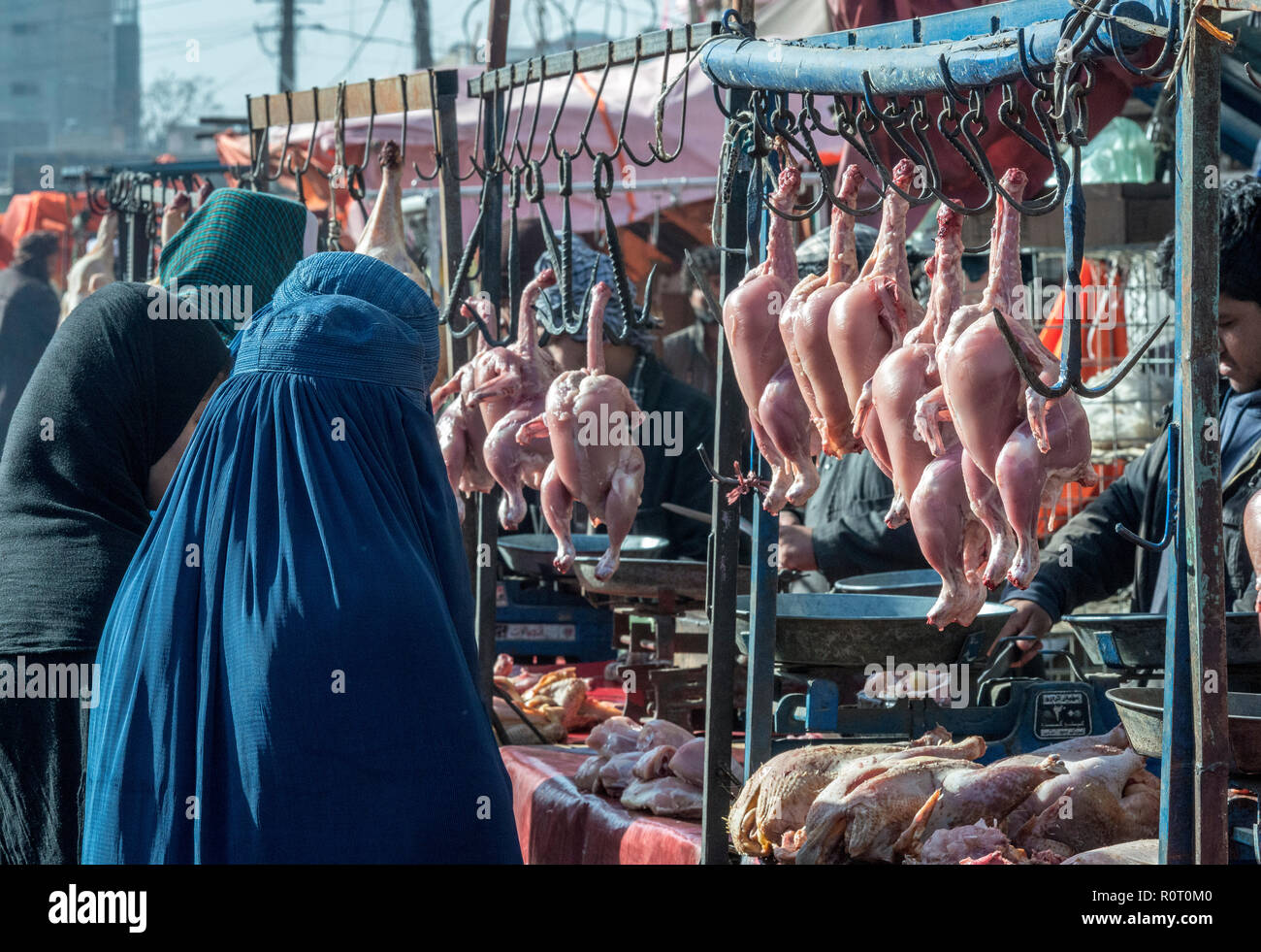 Butcher Selling Skinless Chicken To Women Wearing Blue Burqa At The Mazar-e Sharif Central Bazaar, Maraz-e Sharif, Balkh Province, Afghanistan Stock Photo