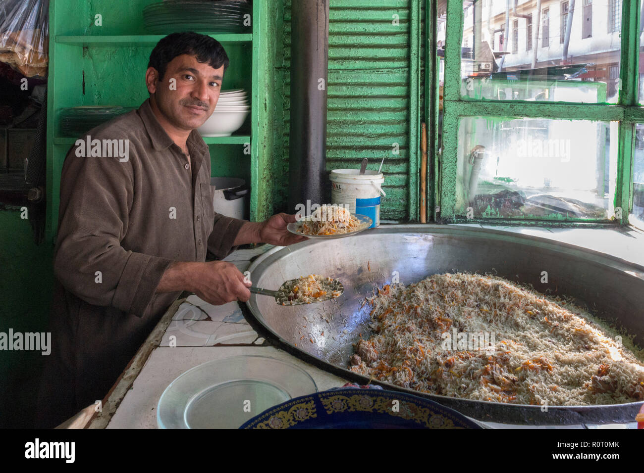 Man Preparing Delicious Biryani In Front Of Green Shutters At The Mazar-e Sharif Central Bazaar, Maraz-e Sharif, Balkh Province, Afghanistan Stock Photo