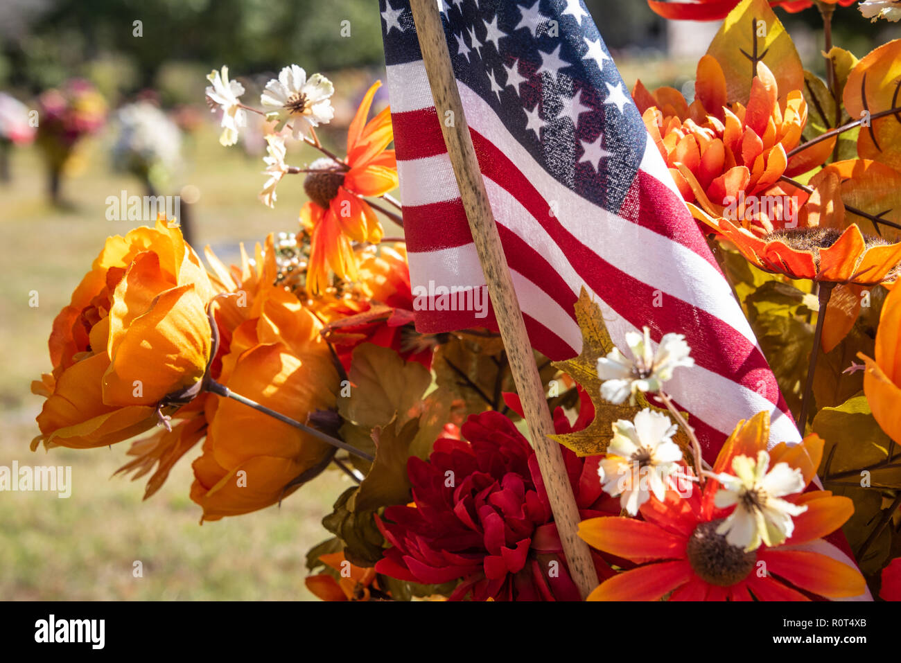 American flag amidst cemetery gravesite flowers. Stock Photo