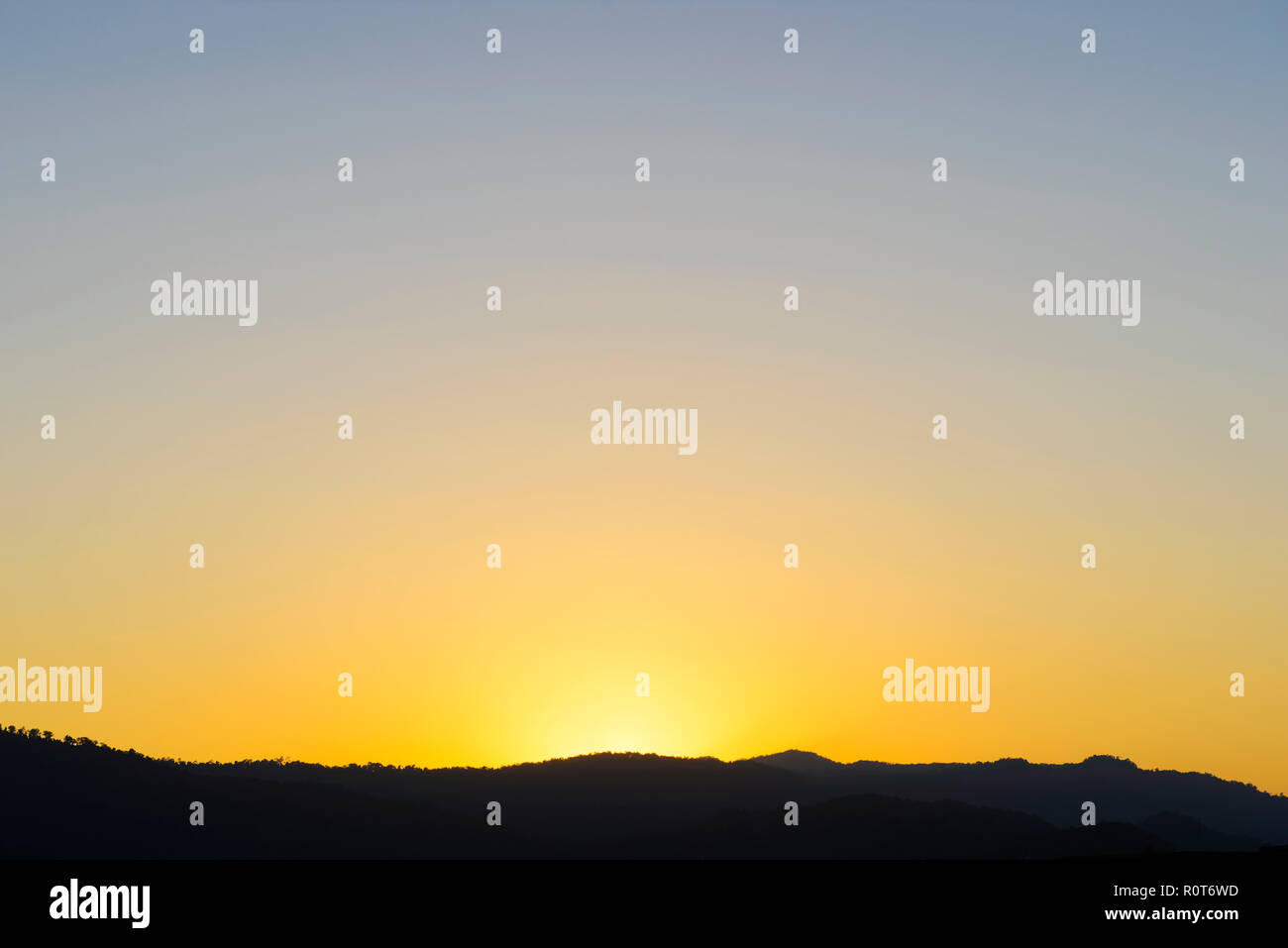 Orange sun setting behind the mountains Stock Photo