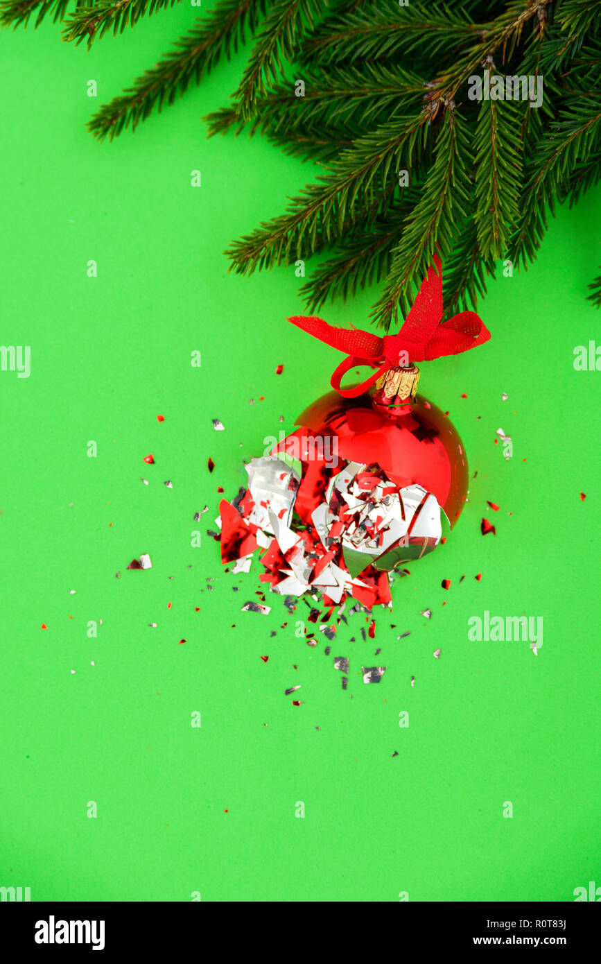 Broken red Christmas ball on green background with tree branch Stock