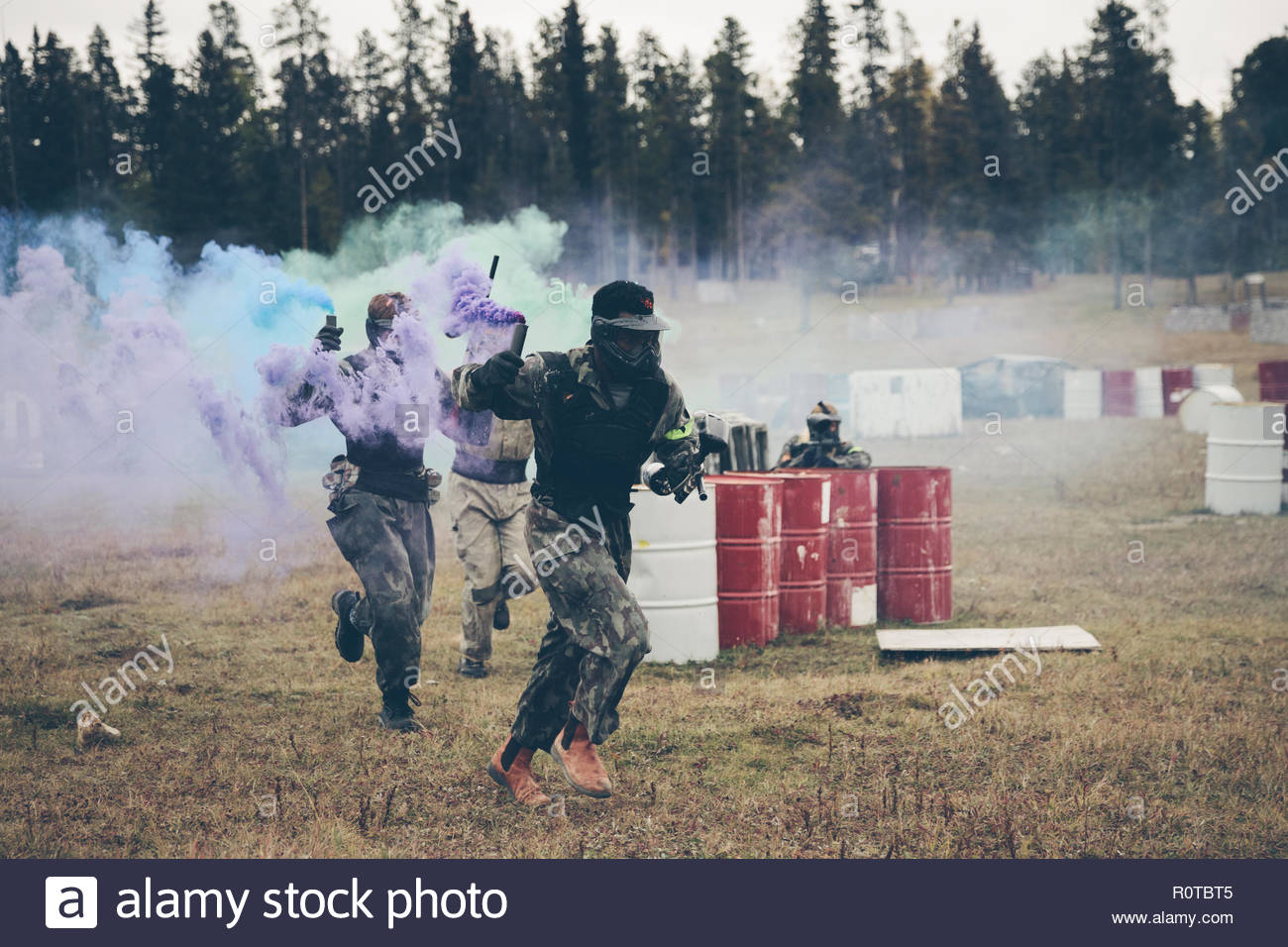 Paintballing team with smoke bombs running in field Stock Photo Alamy