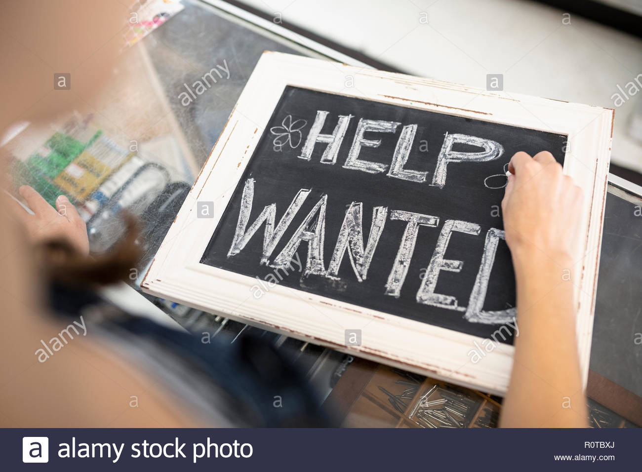 Business owner writing Help Wanted sign on blackboard Stock Photo