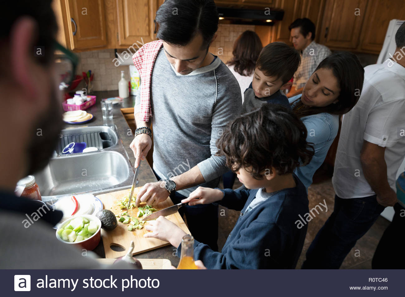 Latinx multi-generation family cooking, cutting avocados in kitchen Stock Photo