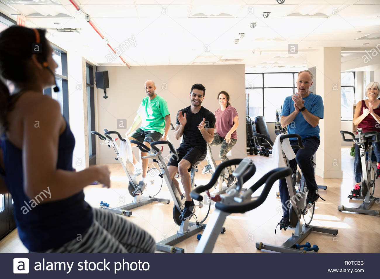 Class clapping for instructor leading spin class in gym Stock Photo