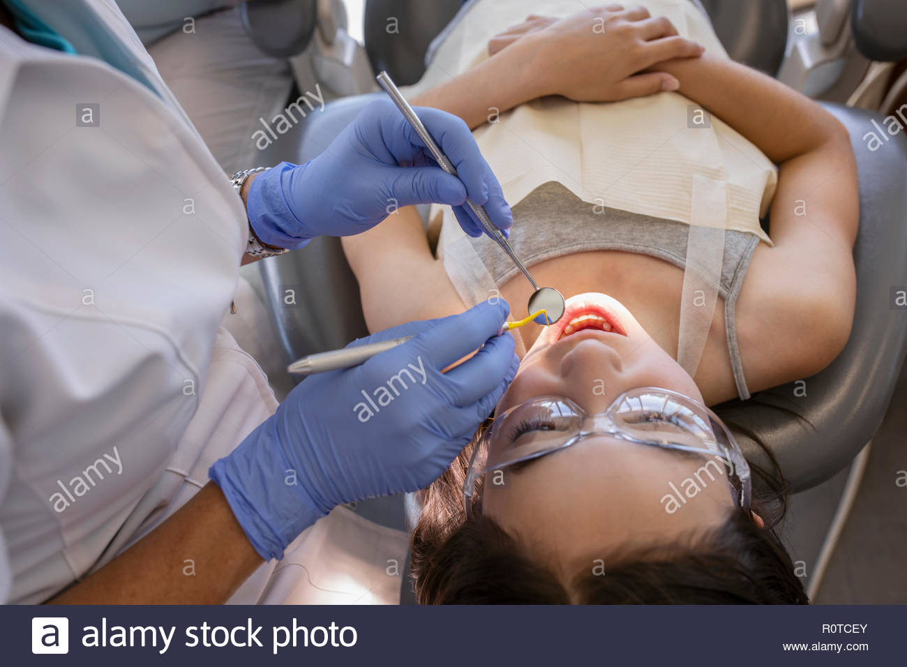 Dental hygienist cleaning teeth of girl in dentist office Stock Photo