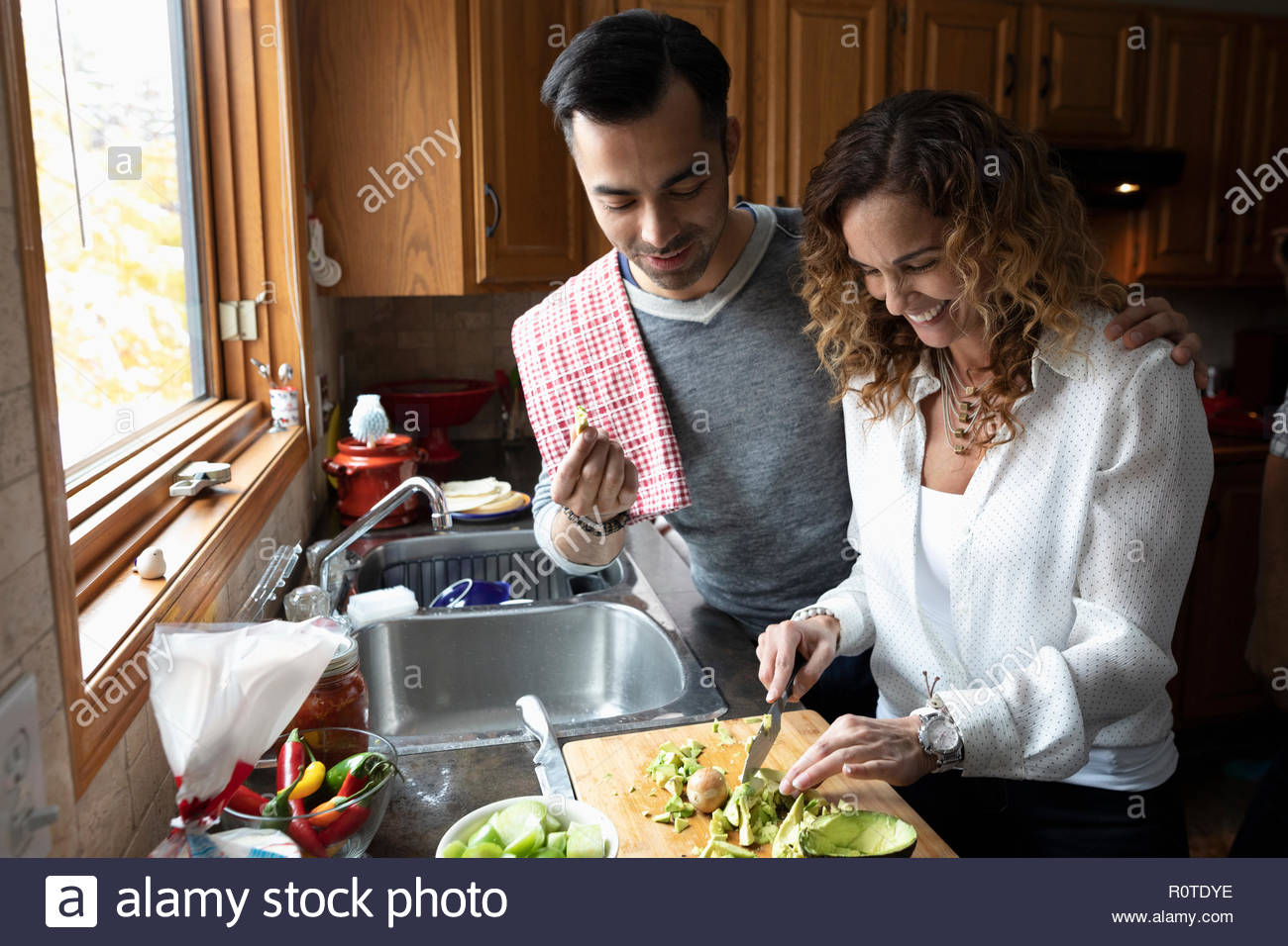 Latinx couple cooking, cutting avocados in kitchen Stock Photo