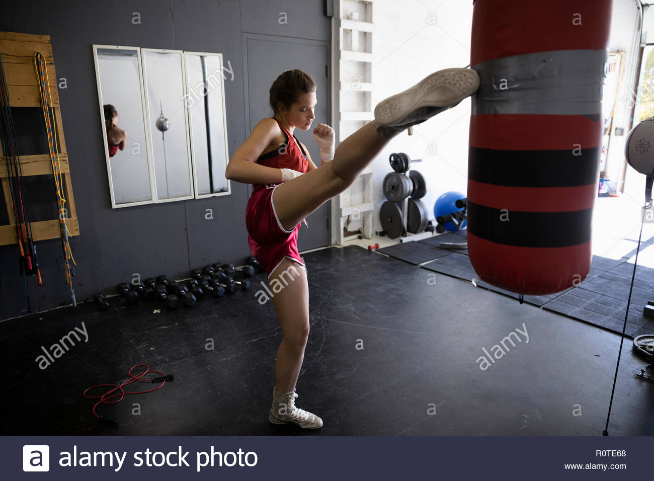 Female kickboxer kicking punching bag in gym Stock Photo