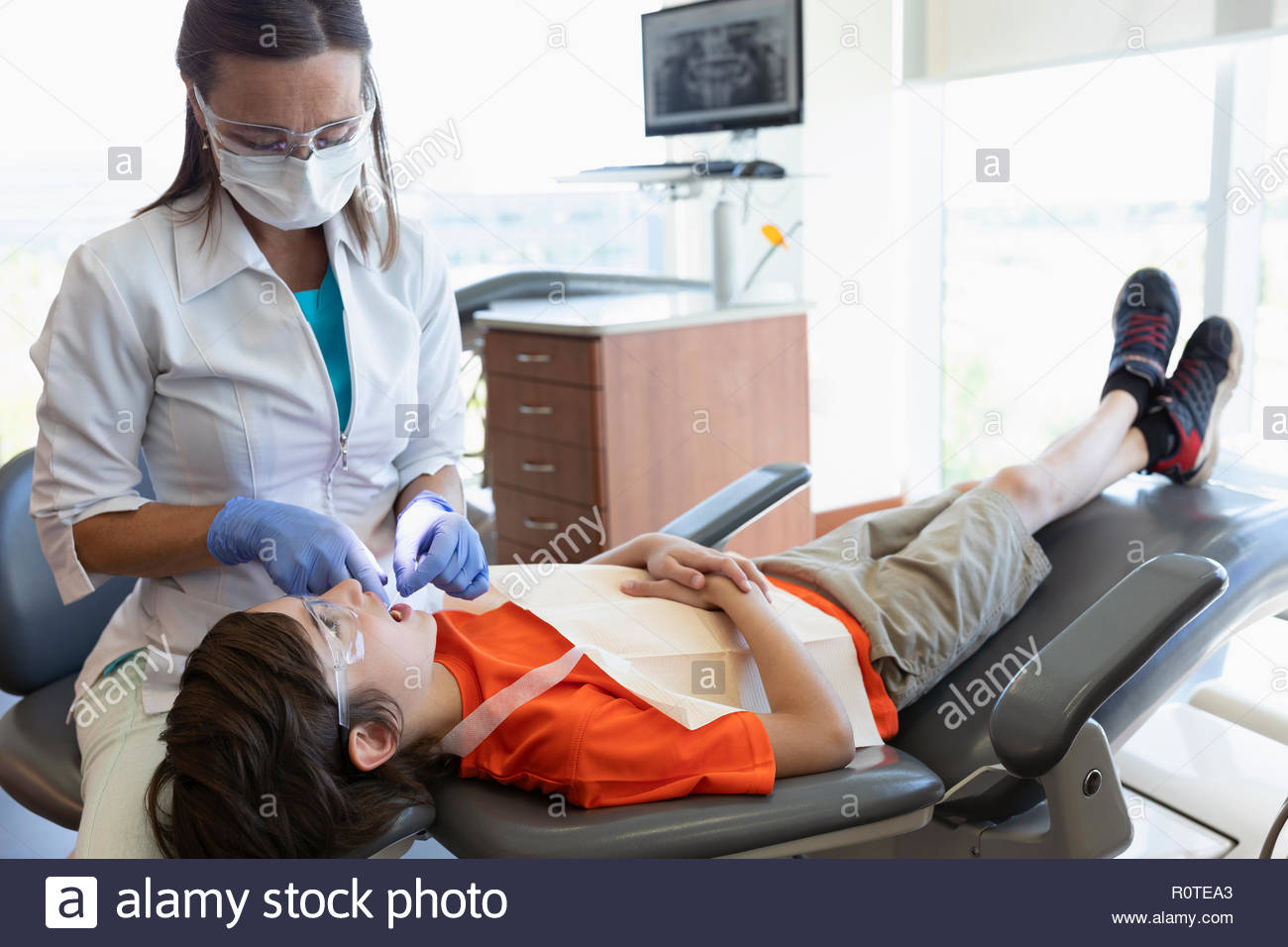Dental hygienist flossing teeth of boy in dentist office Stock Photo