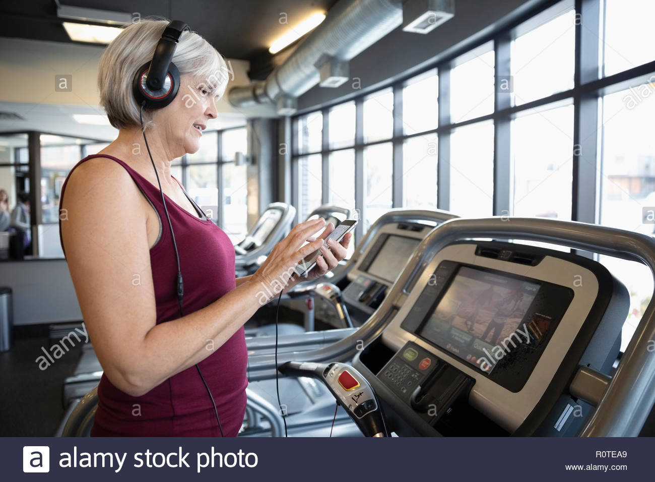 Senior woman with headphones and mp3 player listening to music on