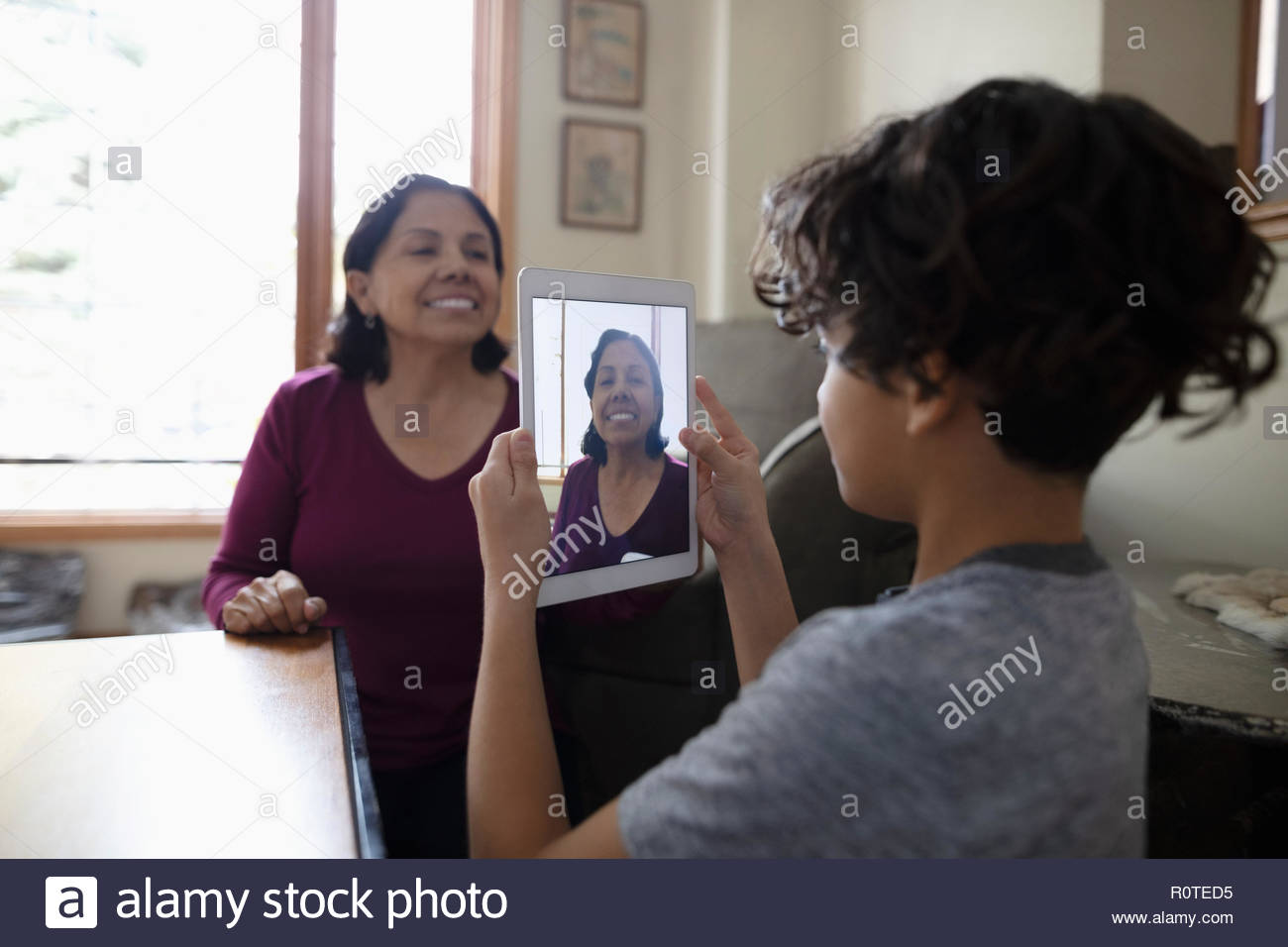 Latinx grandson with digital tablet photographing grandmother Stock Photo