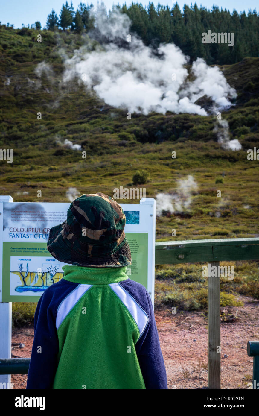 Child reading education information board at the Craters of the Moon (Karapiti in Māori) geothermal walkway, Taupo, North Island, New Zealand Stock Photo