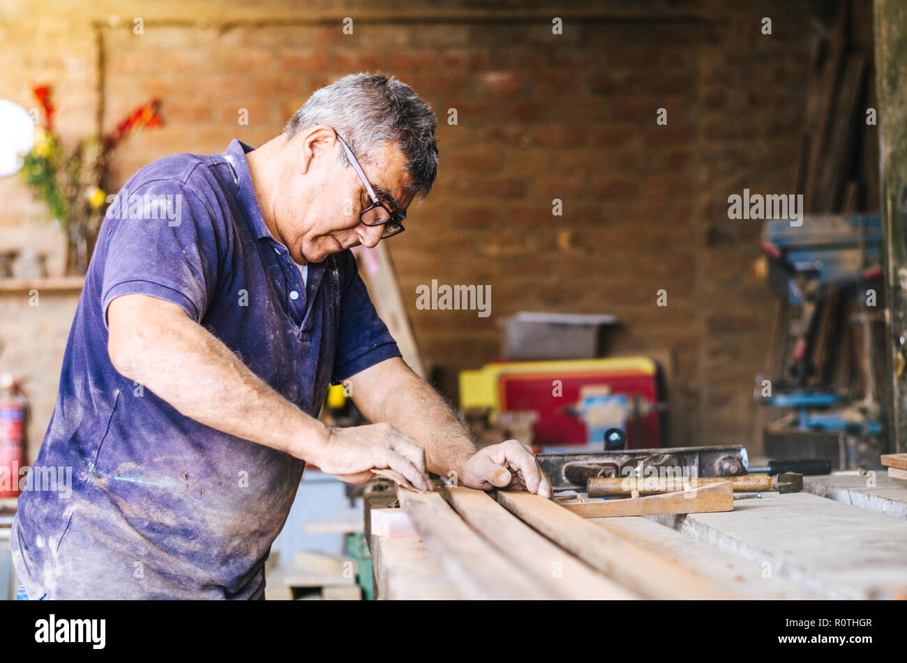 Professional carpenter sanding and restoring wooden surfaces. Stock Photo