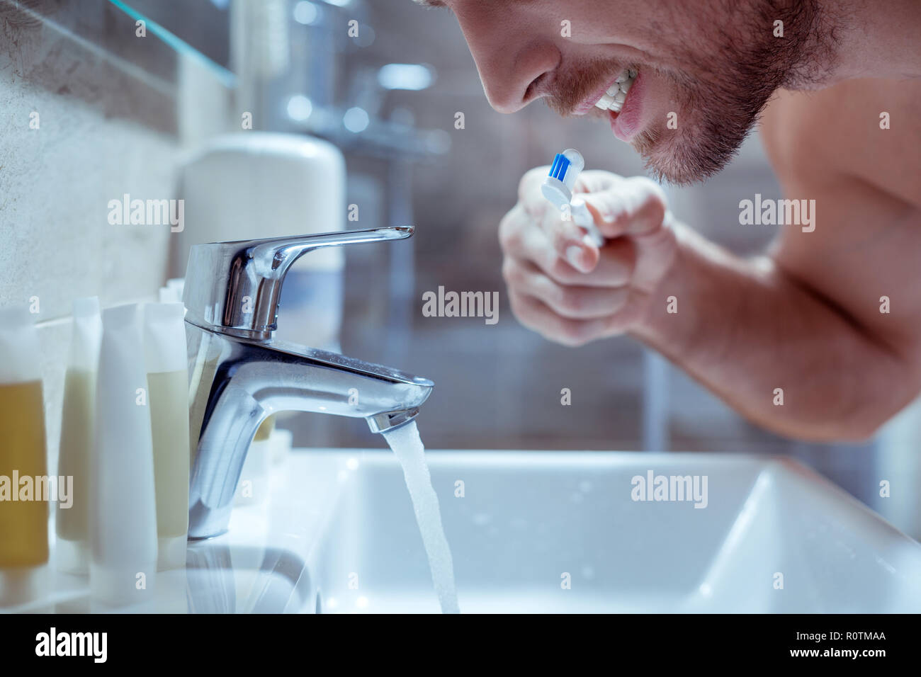 Young handsome bearded man brushing his teeth before going to bed Stock Photo