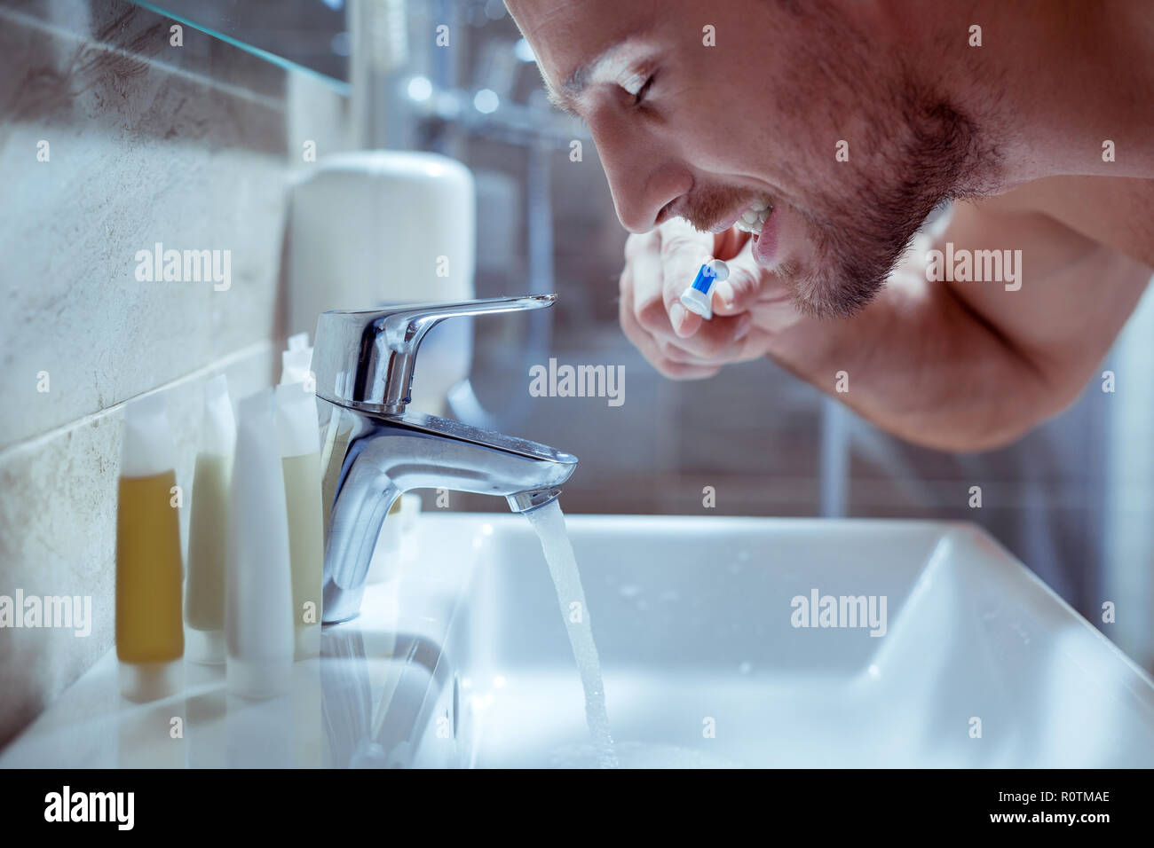 Bearded man closing eyes brushing his teeth and feeling sleepy Stock Photo