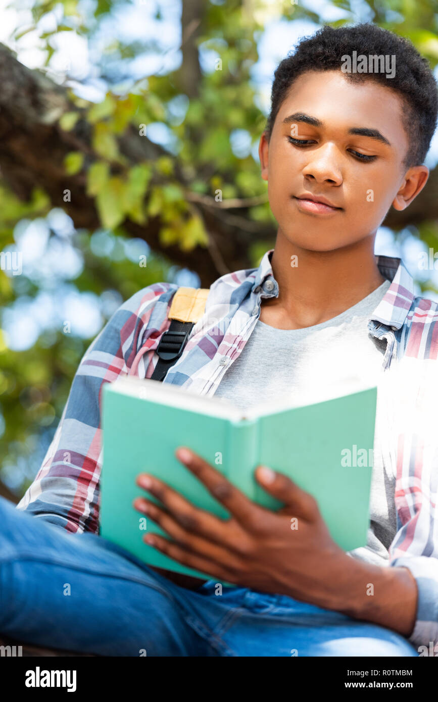 https://c8.alamy.com/comp/R0TMBM/bottom-view-of-focused-teen-student-reading-book-under-tree-R0TMBM.jpg