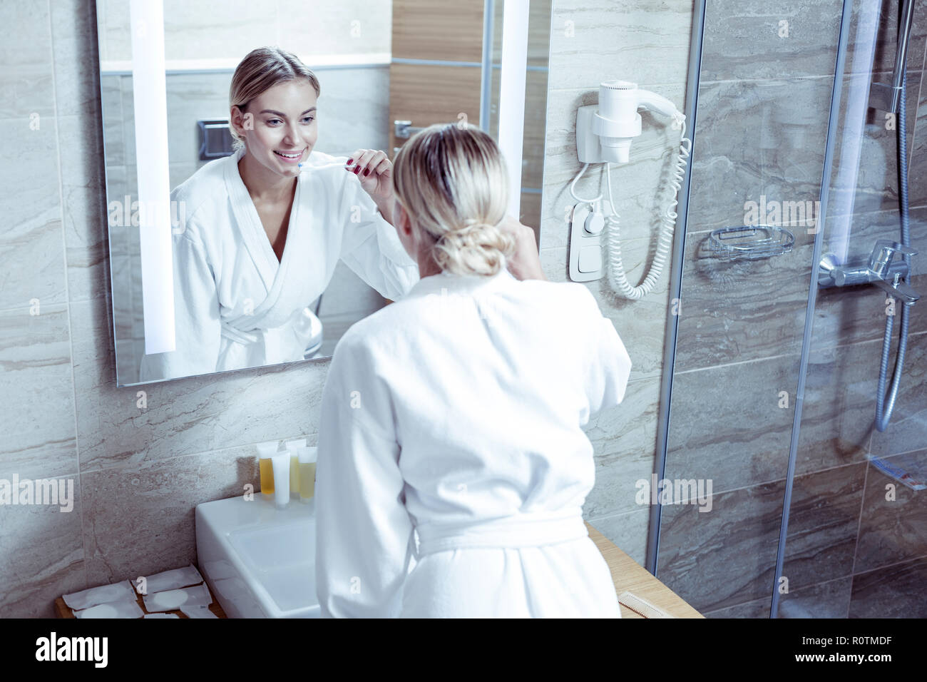 Woman wearing white bathrobe brushing teeth before going to bed Stock Photo