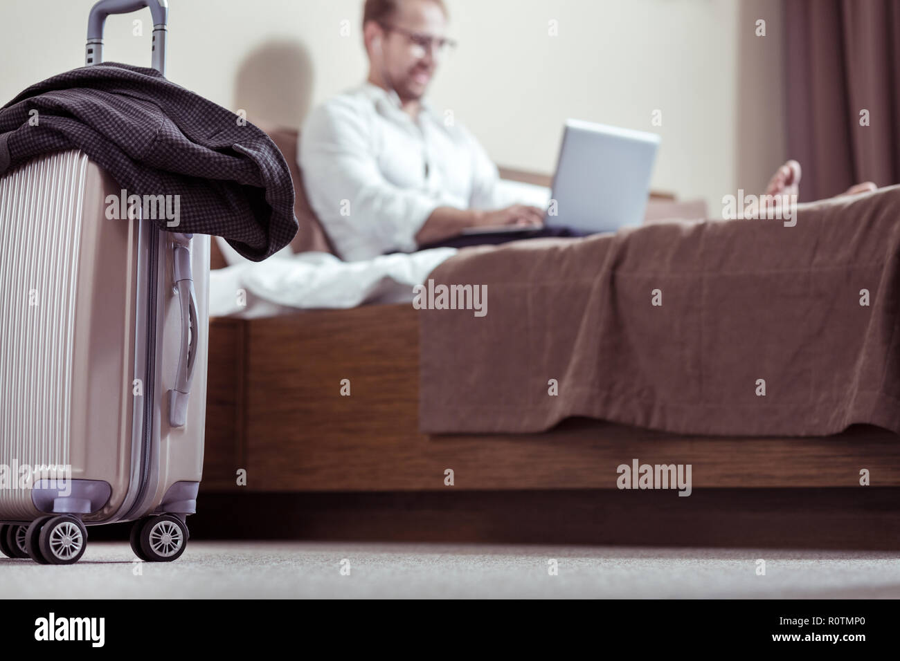 Bearded businessman putting his squared jacket on his luggage Stock