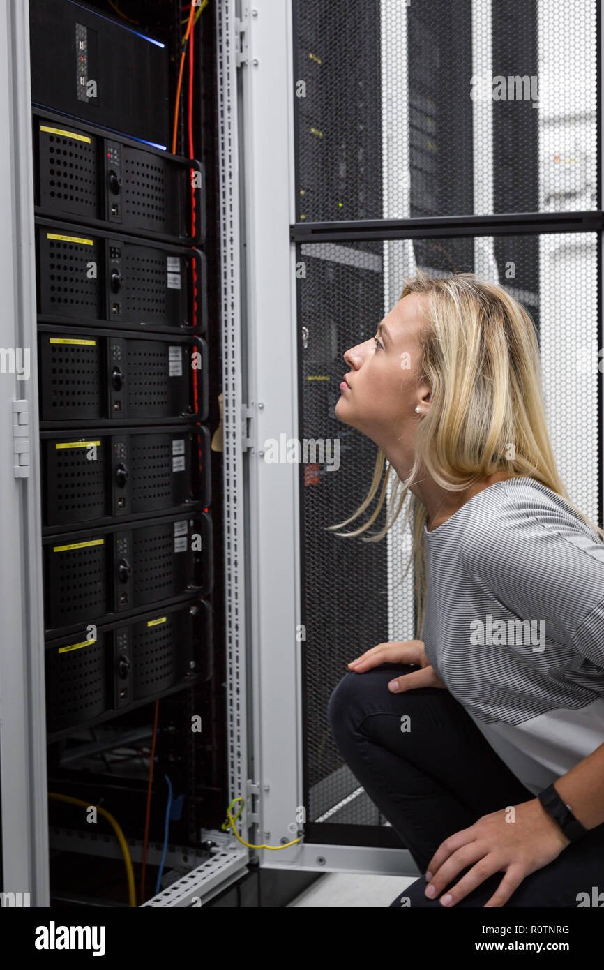 Technician apecialist woman using laptop while analyzing server in server room Stock Photo