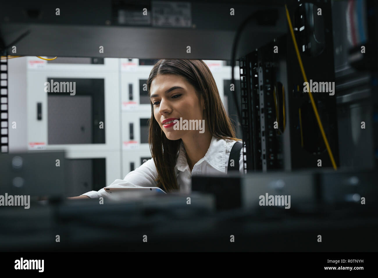 Technician apecialist woman using laptop while analyzing server in server room Stock Photo