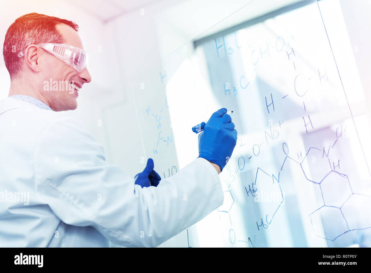 Professional smart man writing a chemical formula on the whiteboard ...