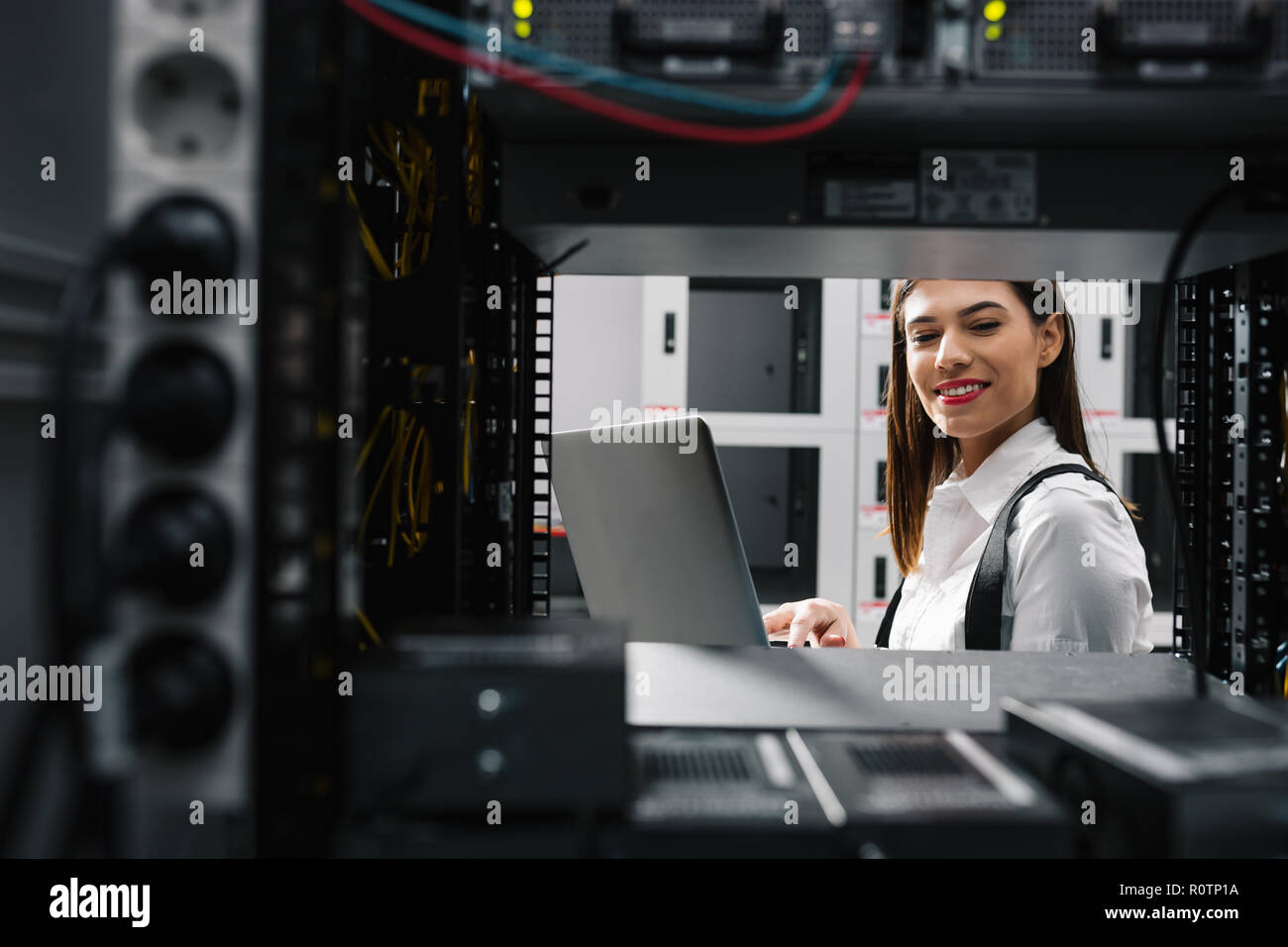 Technician apecialist woman using laptop while analyzing server in server room Stock Photo