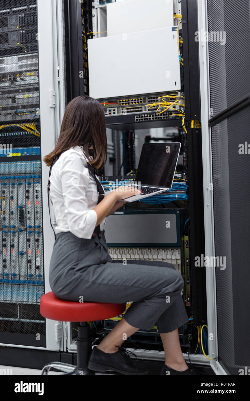 Technician apecialist woman using laptop while analyzing server in server room Stock Photo