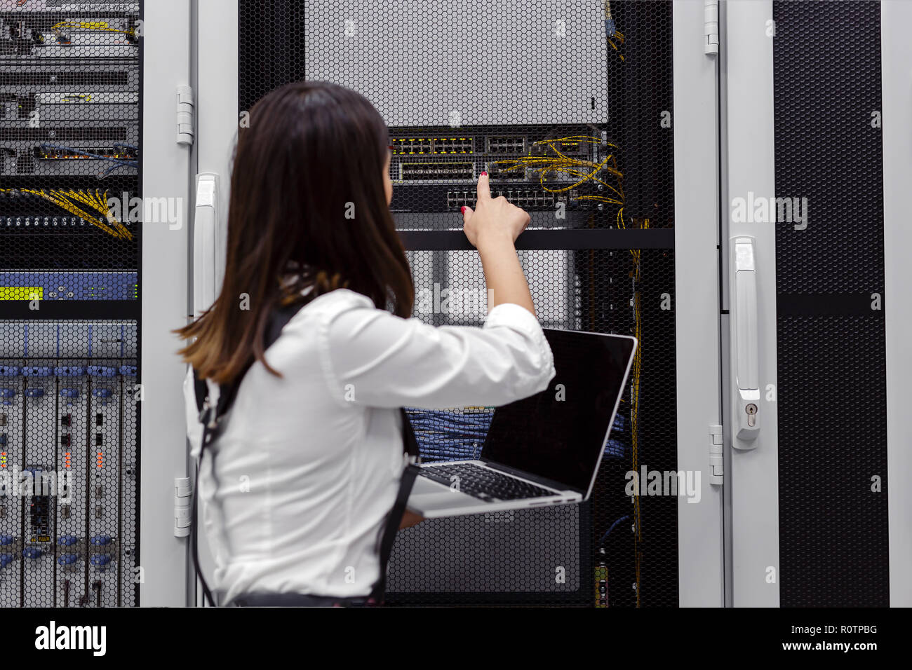 Technician apecialist woman using laptop while analyzing server in server room Stock Photo