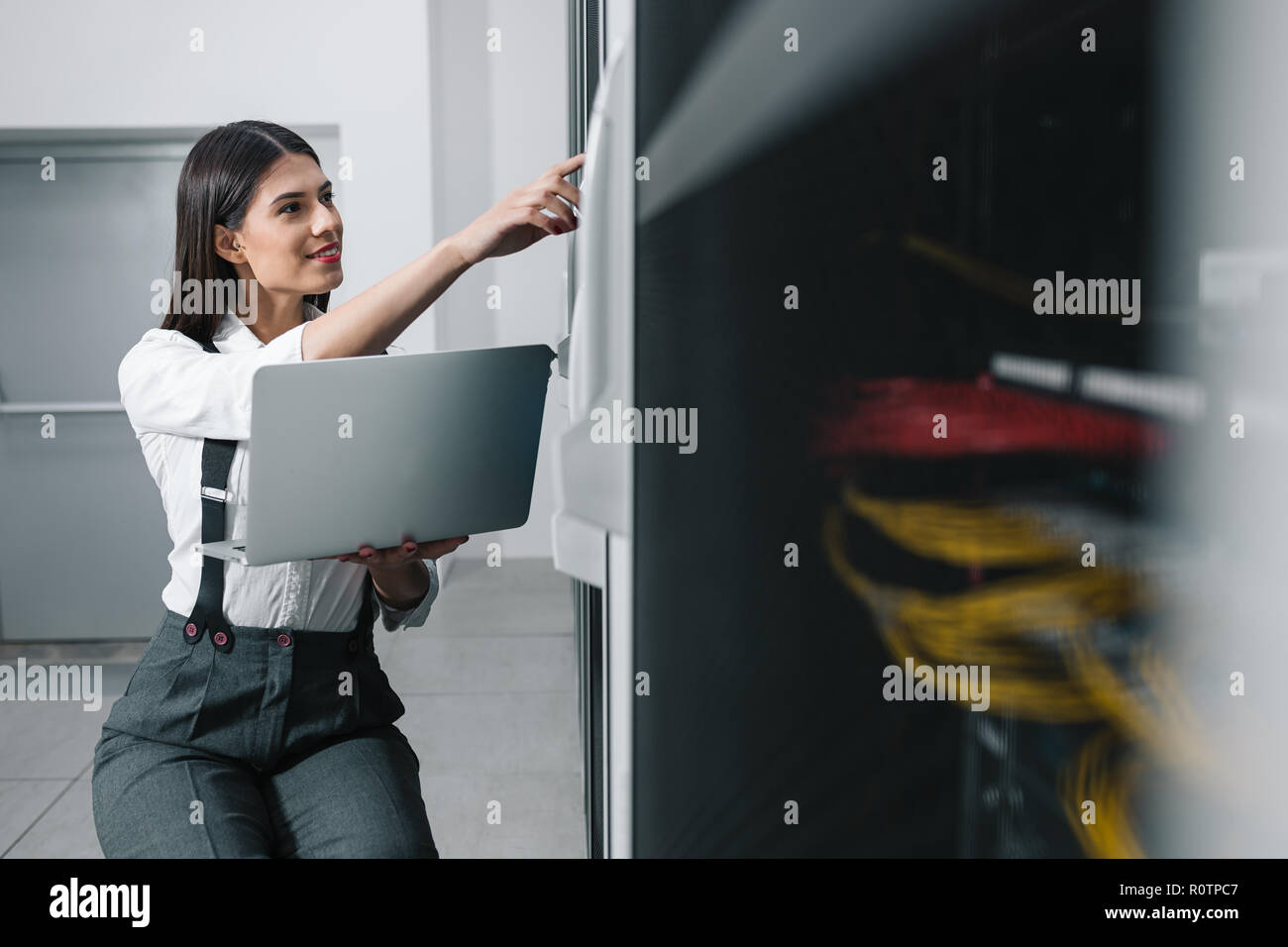 Technician apecialist woman using laptop while analyzing server in server room Stock Photo