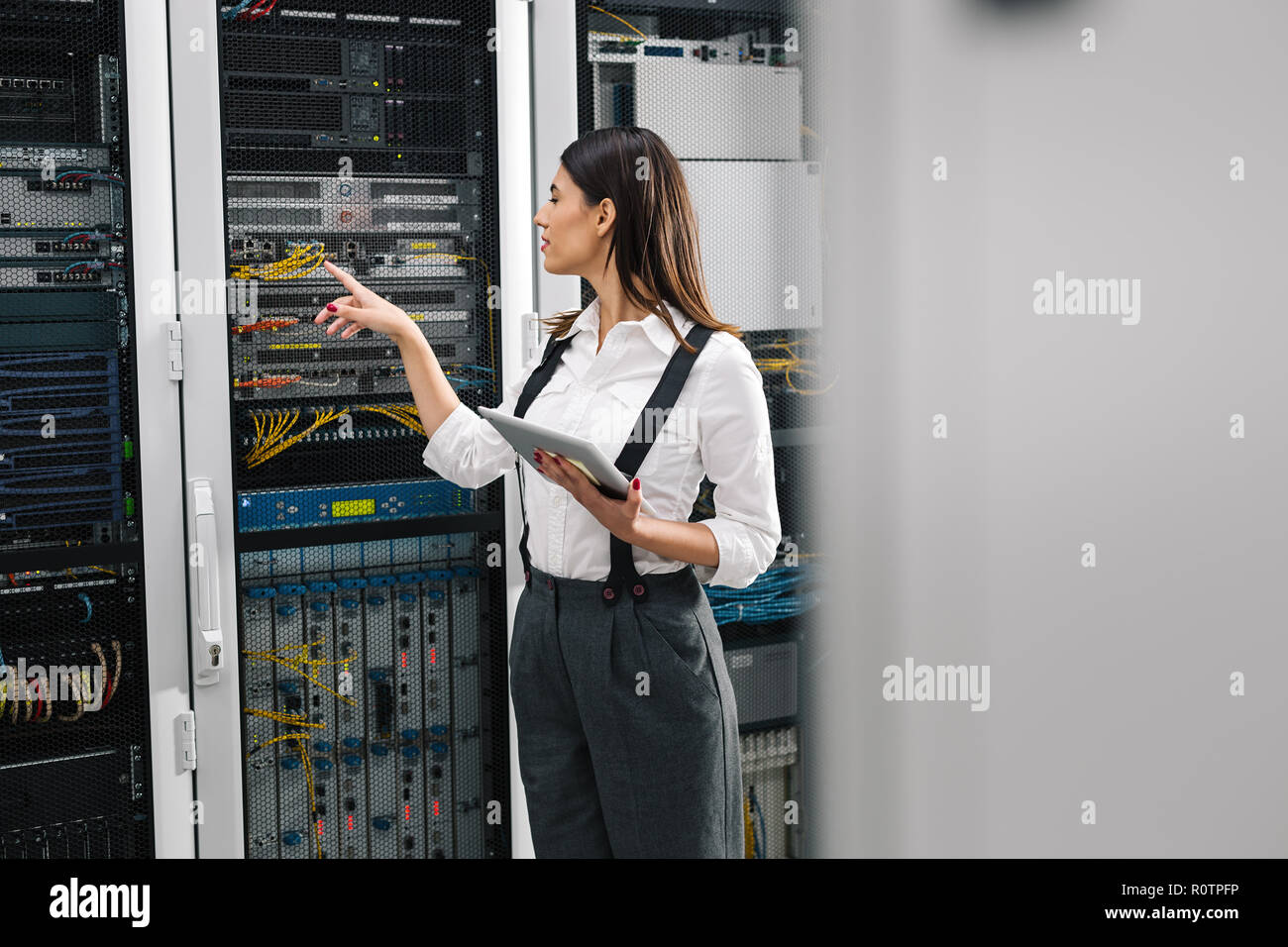 Technician apecialist woman using laptop while analyzing server in server room Stock Photo