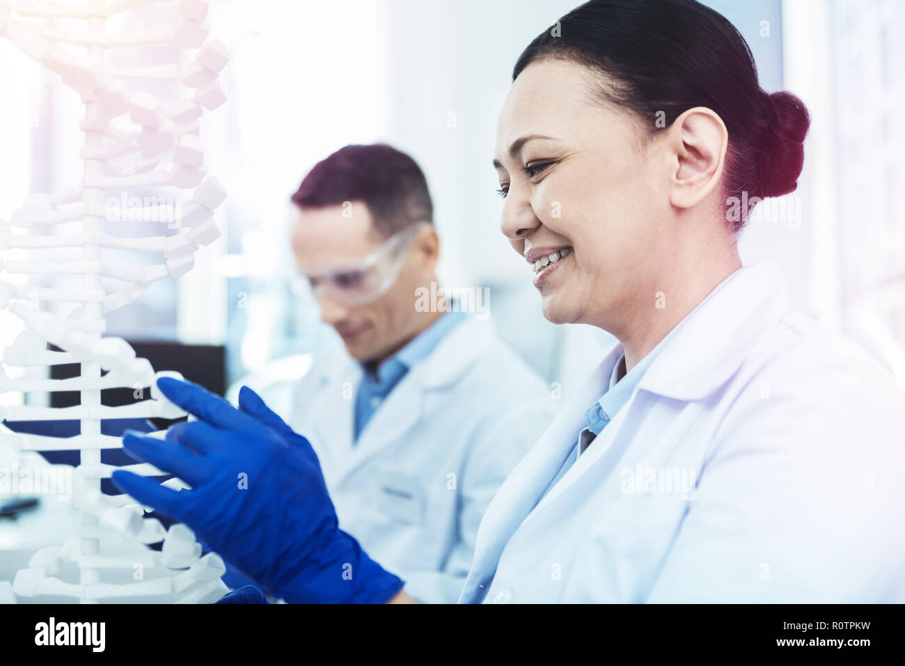 Cheerful delighted woman looking at the DNA model Stock Photo