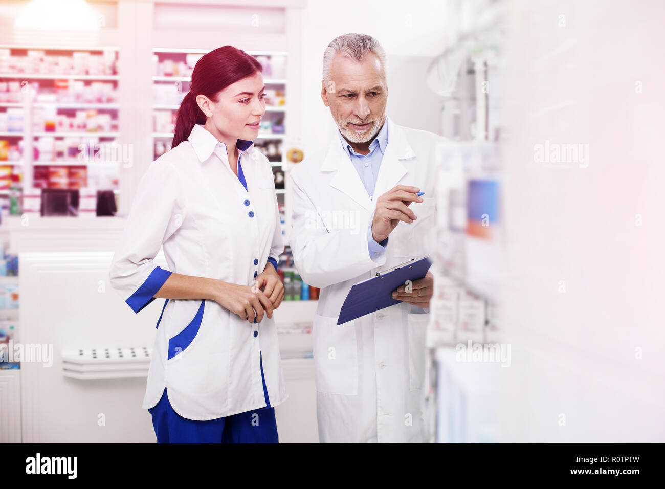 Main pharmacist helping a young improver with products Stock Photo