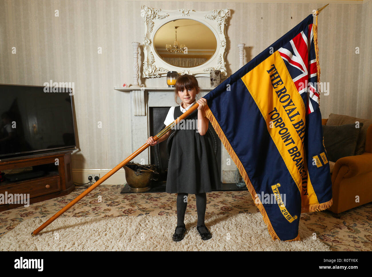 Mollie Stonelake, seven, holds a full-size standard from the Torpoint & District Branch of the Royal British Legion in her family home in Torpoint, Cornwall. Mollie went on her first parade aged five and will carry a specially-made miniature standard in a service on Sunday in her home town of Torpoint in Cornwall. Stock Photo