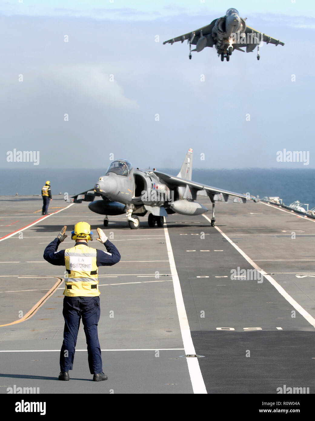 HARRIER of No 1 (F) Squadron RAF  landing on in board HMS Illustrious whilst another waits its turn during Exercise Joint Warrior in 2008.Photo: Cpurtesy MOD 45149691. Stock Photo