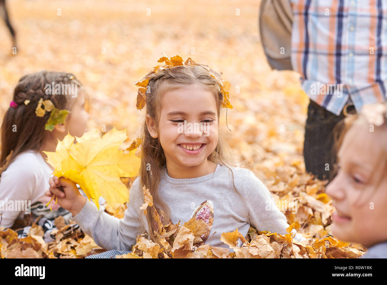 Children are lying and playing on fallen leaves in autumn city park ...