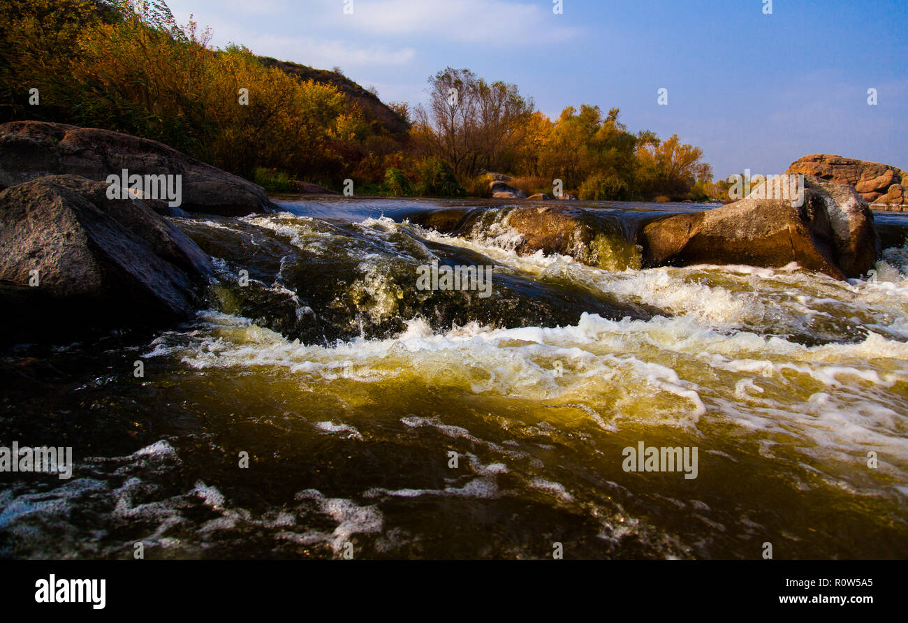 powerful stream of water goes around stone rapids with splashes and