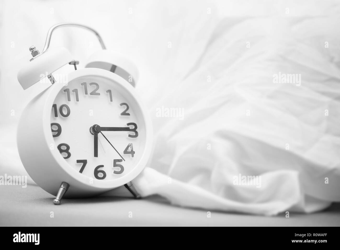 Time background concept. Alarm clock on bed, wake up in the morning. Picture for add text message. Backdrop for design art work. Stock Photo