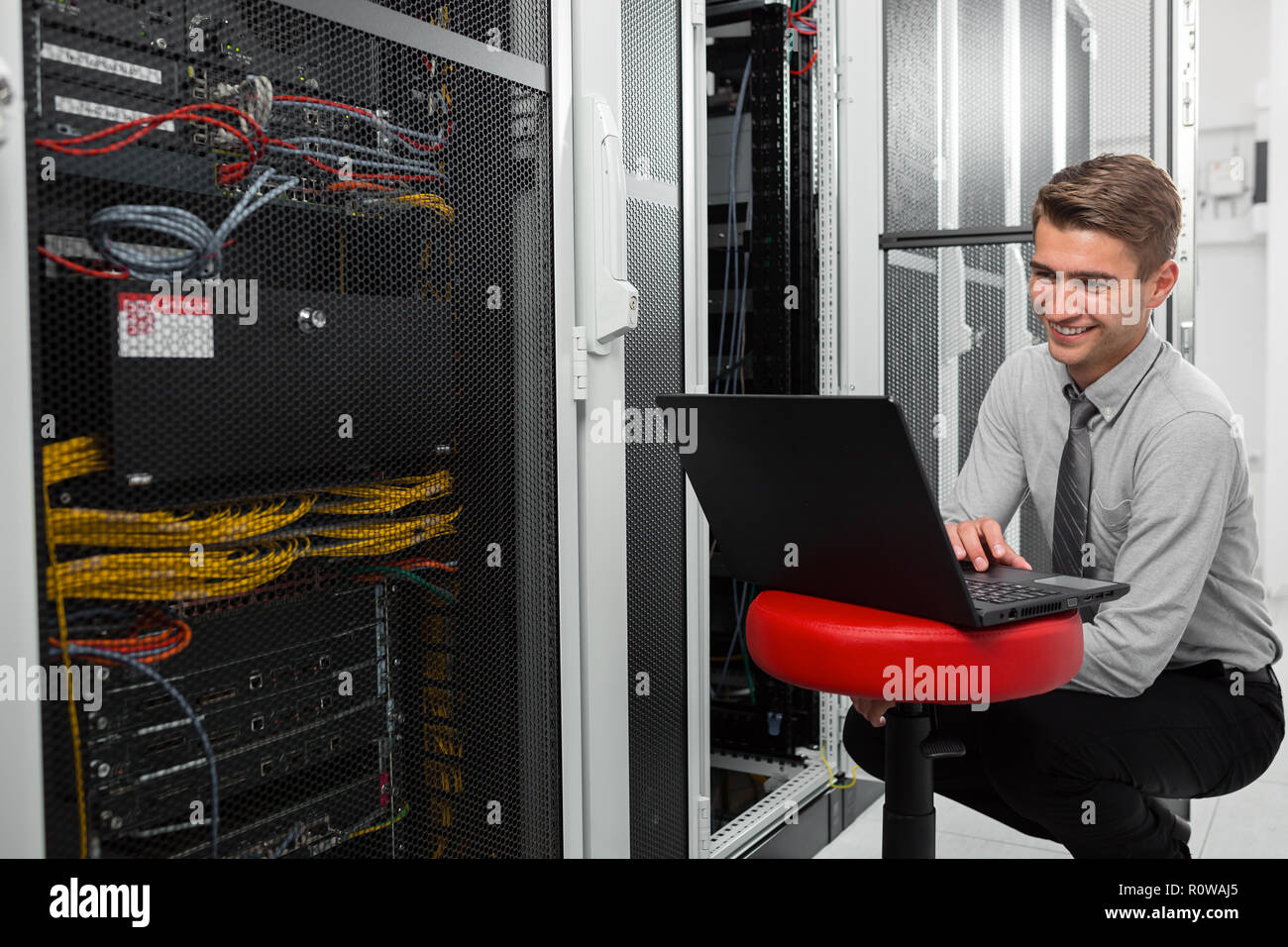 Male Server Engineer Works on a Laptop in Large Data Center Stock Photo ...