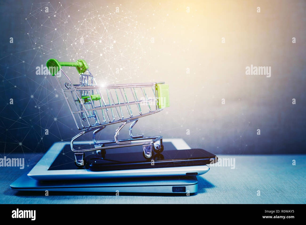 Online shopping background. E-commerce marketing technology, shopping cart on stacked mobile, tablet and laptop with connection line icon. Worldwide b Stock Photo