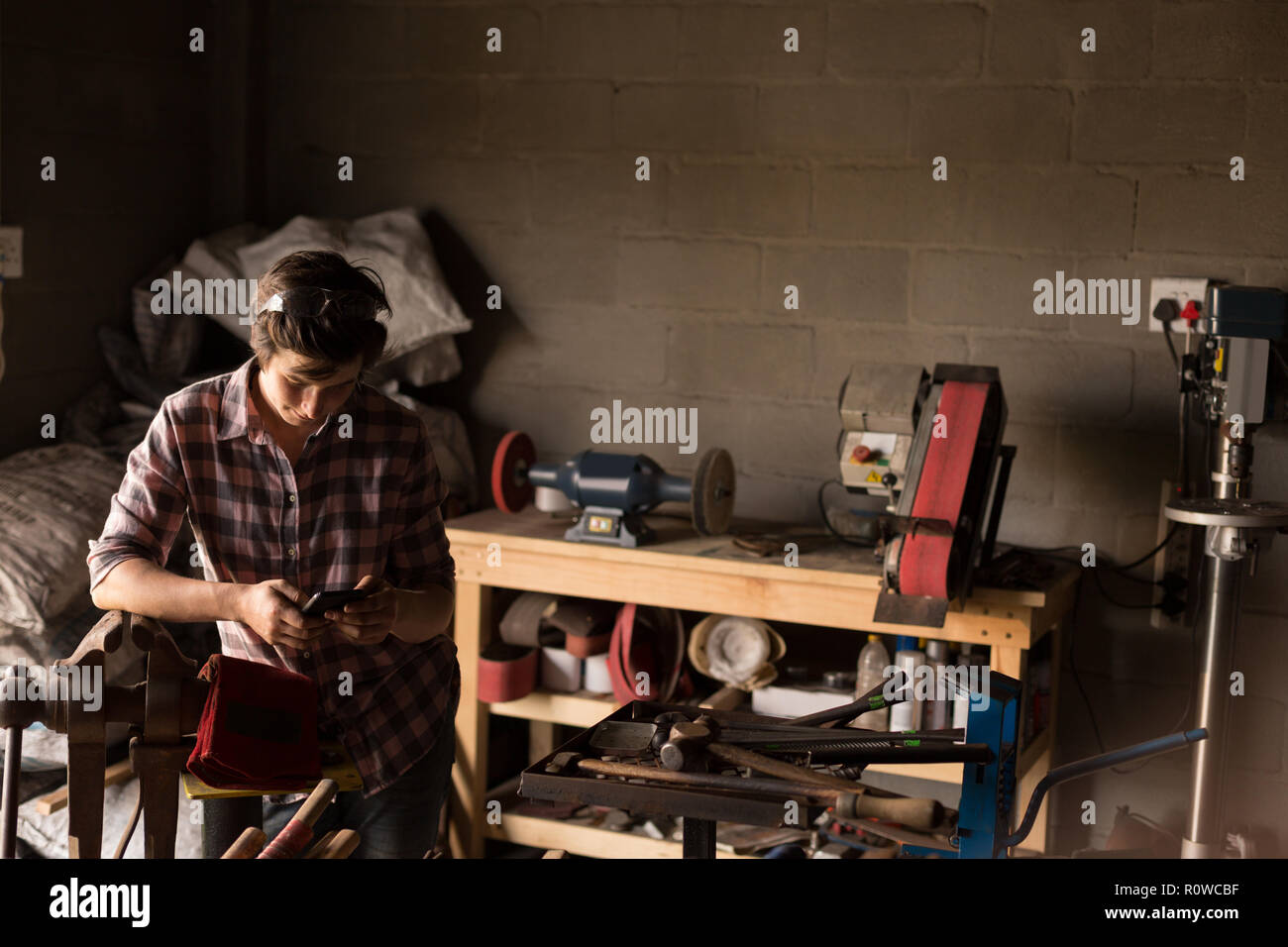 Female Metalsmith using mobile phone Stock Photo