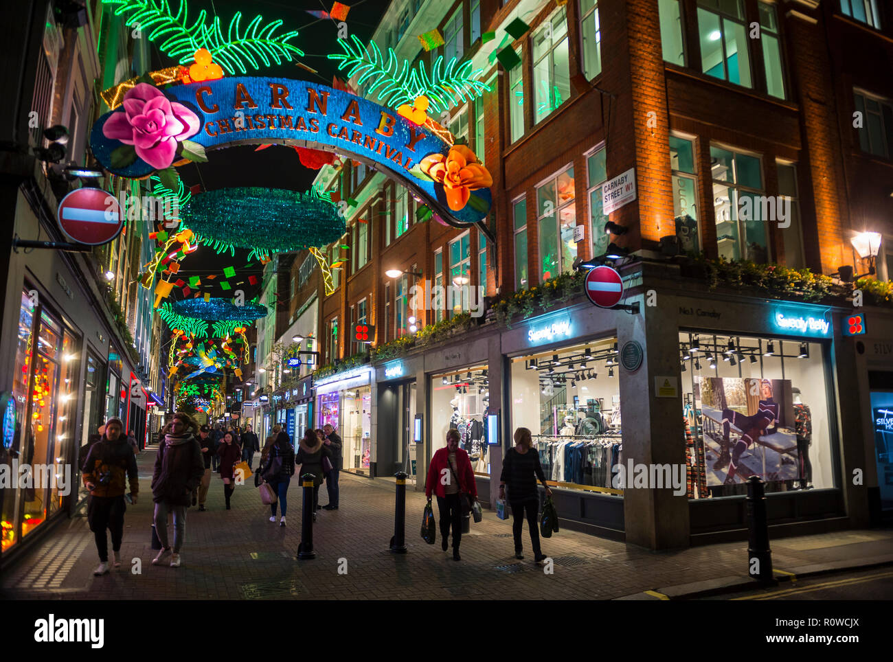 LONDON - CIRCA DECEMBER, 2017: Holiday crowds pass under Carnival themed Christmas signs in the pedestrianized shopping district of Carnaby Street. Stock Photo