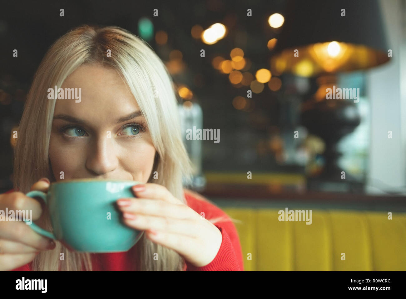 Woman sipping coffee in cafeteria Stock Photo