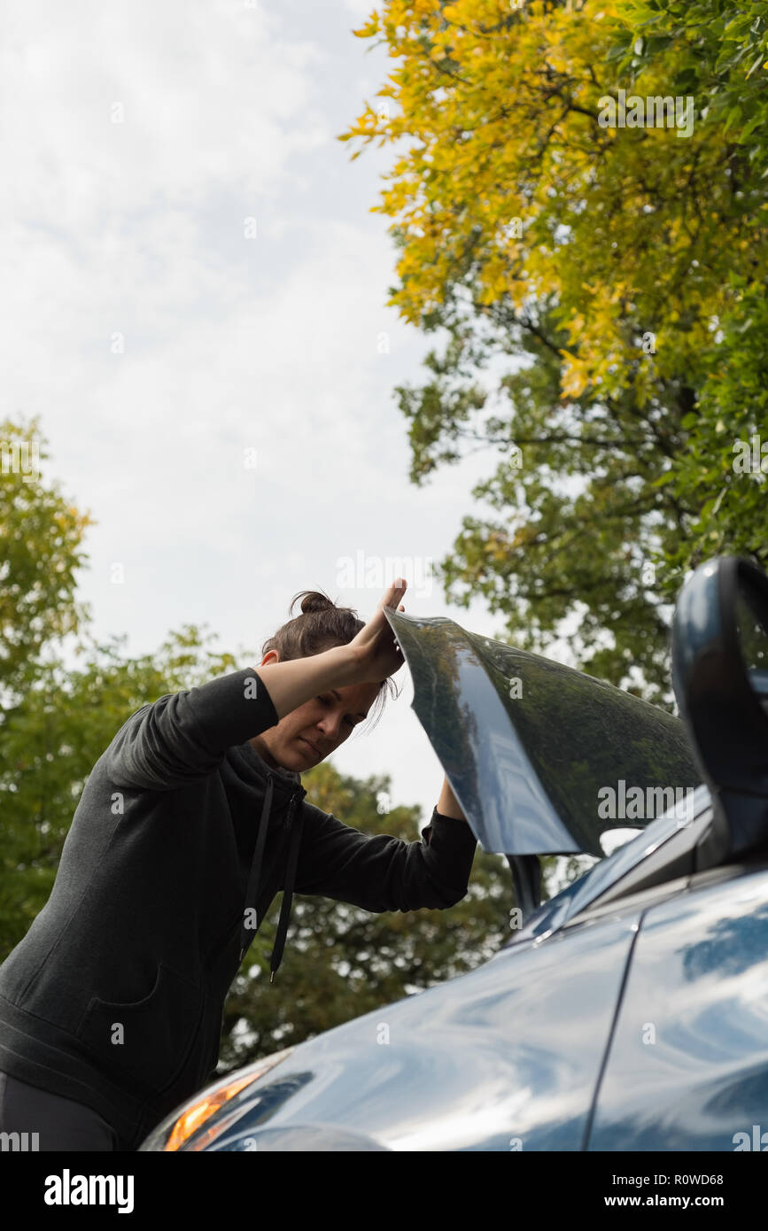 Woman checking a car during breakdown Stock Photo