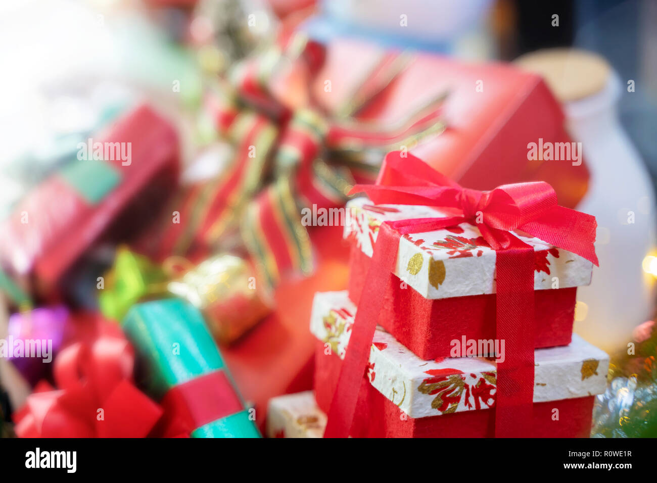 Merry Christmas background concept. Closeup of red gift box with blurred another gift boxes in background. Stock Photo