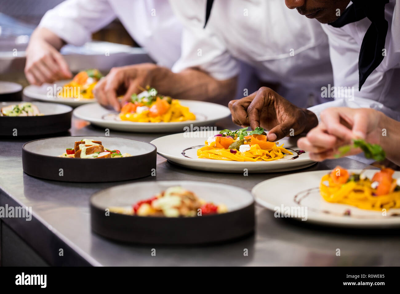 Chef garnishing food on plates Stock Photo